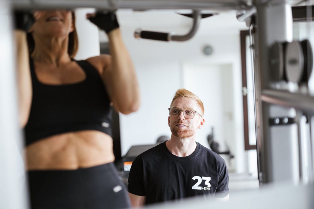 Frau macht Klimmzug im Fitnessstudio