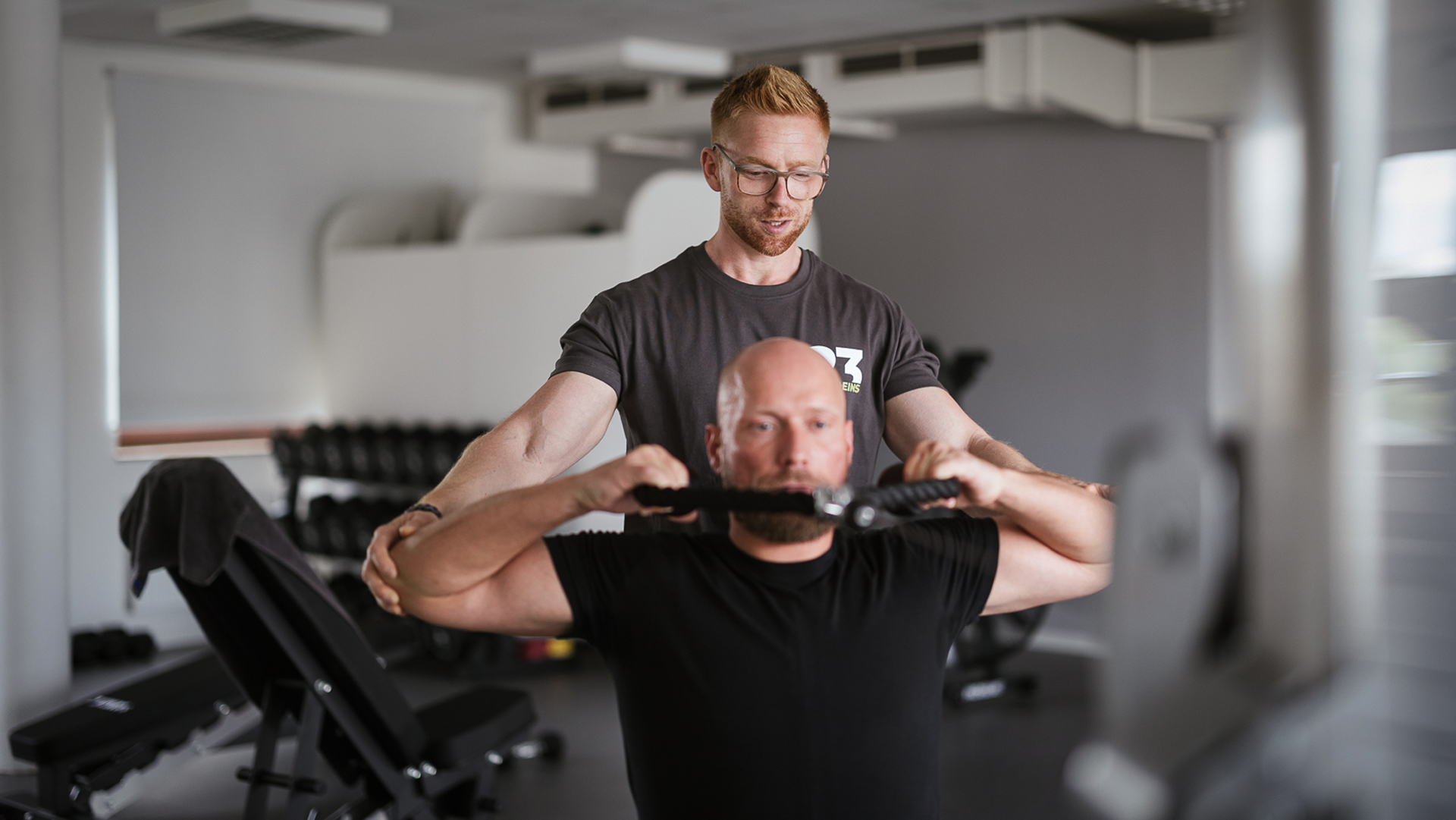 Personal Trainer trainiert Mann im Fitnessstudio